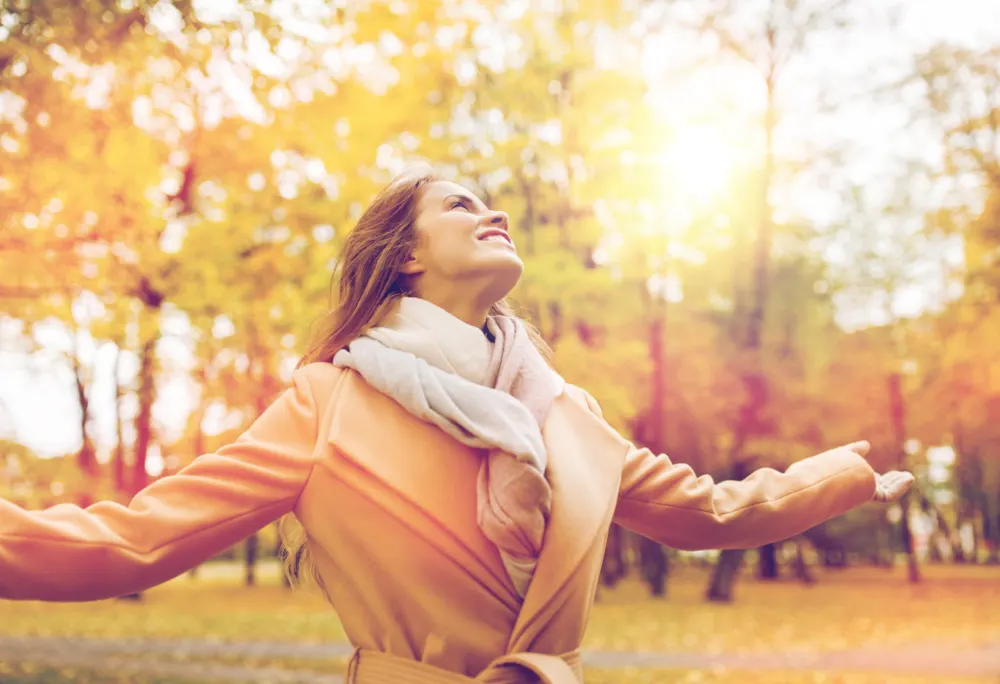 <p>Happy woman in a coat enjoying life in an autumn park.</p>